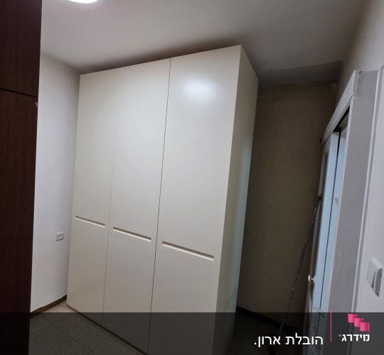 ארון לבן גדול בחדר עם מטאטא בצד